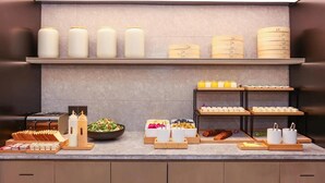 A buffet setup with various food items, condiments, and a salad.