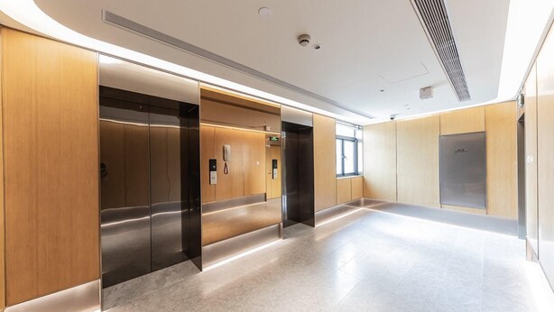 A modern elevator area with wooden paneling and a marble floor.