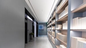 A modern hallway with a long, narrow layout, featuring a central walkway flanked by bookshelves on both sides.