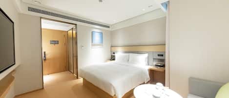 A hotel room with a bed, bedside table, and a television.