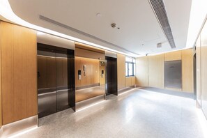 A modern elevator area with wooden paneling and a marble floor.