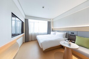 Una habitación de hotel con cama, mesita de noche y vistas al exterior.