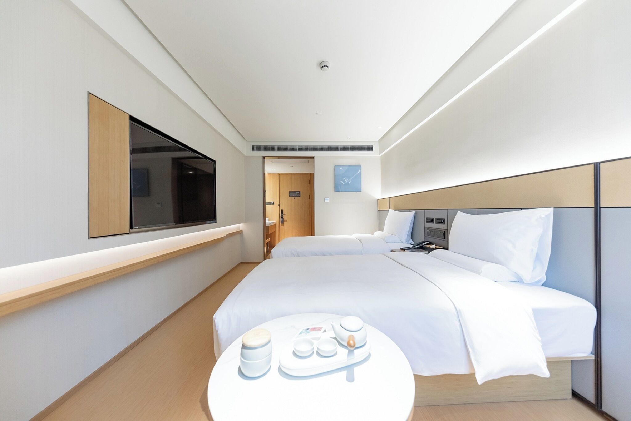 Una habitación de hotel moderna con una cama, mesita de noche y un televisor montado en la pared.