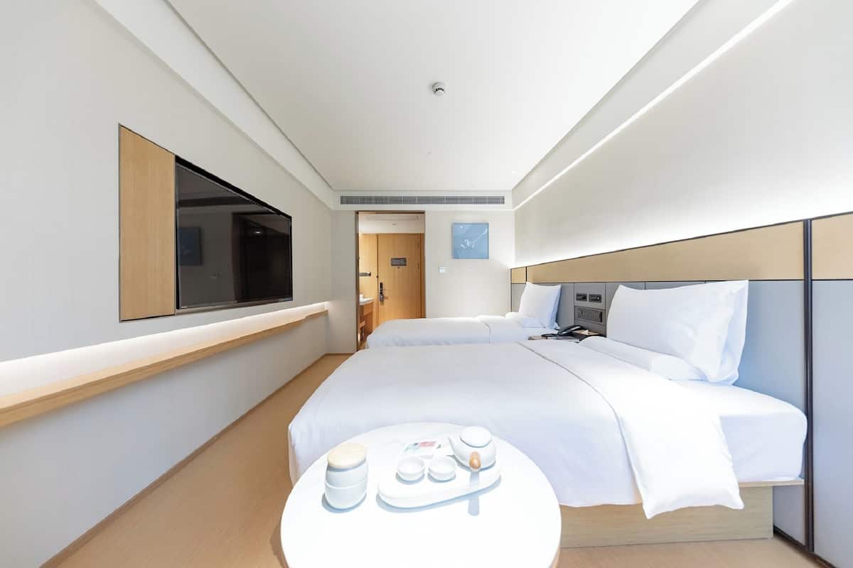 Una habitación de hotel moderna con una cama, mesita de noche y un televisor montado en la pared.