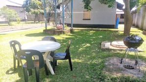 Een achtertuin met een tafel en stoelen, een barbecue en een boom.