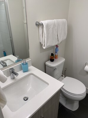 Une salle de bain moderne avec un lavabo blanc, un miroir, des toilettes et un porte-serviettes.
