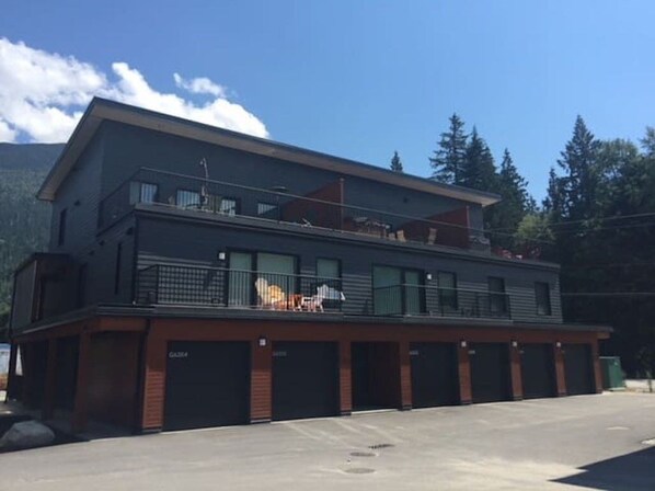 Un bâtiment moderne à deux étages, doté d’un toit plat, de plusieurs portes de garage et d’un balcon à l’étage supérieur.