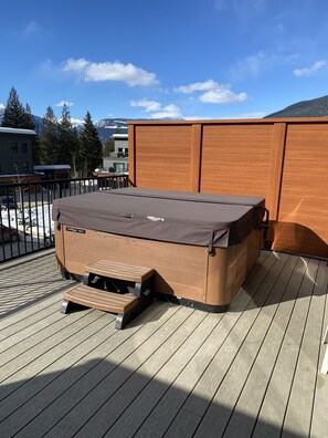 Une terrasse en bois avec un barbecue et un espace salon abrité.
