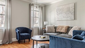 Een woonkamer met een blauwe fauteuil, een grijze bank en een salontafel.