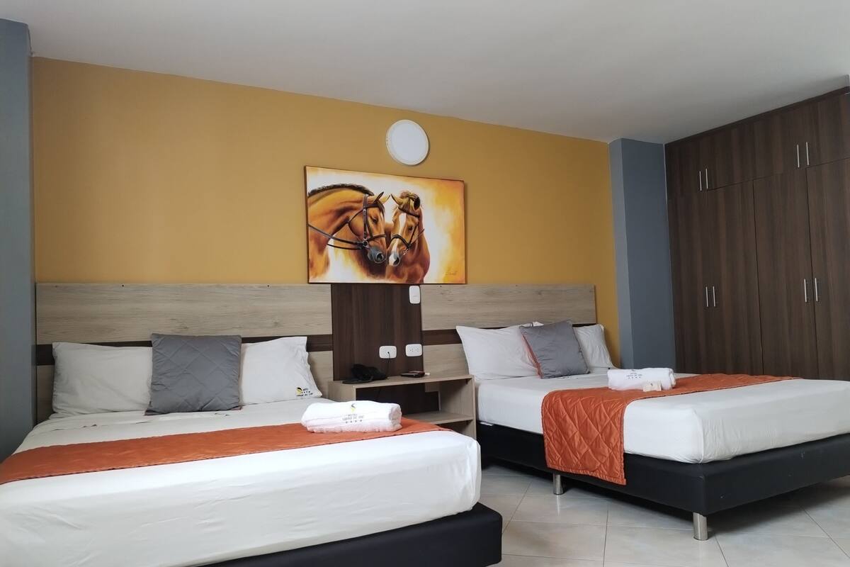Ein Hotelzimmer mit zwei Betten, einem hölzernen Kopfteil, einem Bild von Pferden, einem Kleiderschrank und einem Nachttisch mit Lampe.