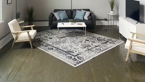 A living room with a sofa, two chairs, a coffee table, a TV, and two framed pictures on the wall.