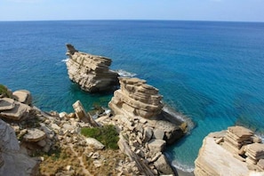 Paisagem costeira com formações rochosas e mar azul cristalino.