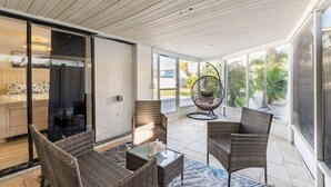 Eine sonnendurchflutete Terrasse mit Korbmöbeln, einem Hängesessel und einem Glastisch.