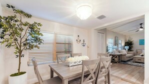 Ein Essbereich mit Holztisch, vier Stühlen, einem Blumentopf und einer Deckenleuchte.
