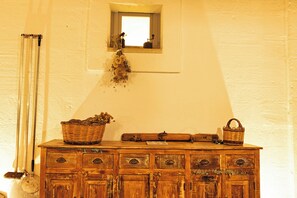 A rustic wooden dresser with a mirror above it, a broom leaning against the wall, and a basket on the dresser.