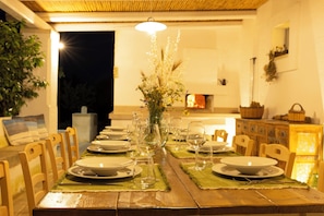 A dining table set with plates, glasses, and a vase of flowers, with chairs around it. - Masseria Ferarelli Trepizzi (Diso)
