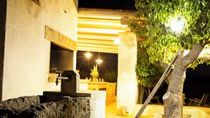 An outdoor dining area with a stone fountain, a wooden table, and chairs. - Masseria Ferarelli Trepizzi (Diso)