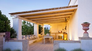 An outdoor patio area with a covered seating area, a table, and a fireplace. - Masseria Ferarelli Trepizzi (Diso)