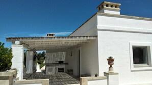 A white building with a covered patio area, a window, and a potted plant. - Masseria Ferarelli Trepizzi (Diso)