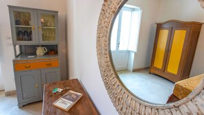 A room with a grey cabinet, a wooden table with a book, and a mirror with a brick frame. - Masseria Ferarelli Trepizzi (Diso)