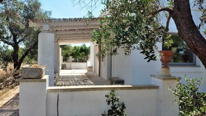 A covered outdoor area with a pergola, stone steps, and potted plants. - Masseria Ferarelli Trepizzi (Diso)
