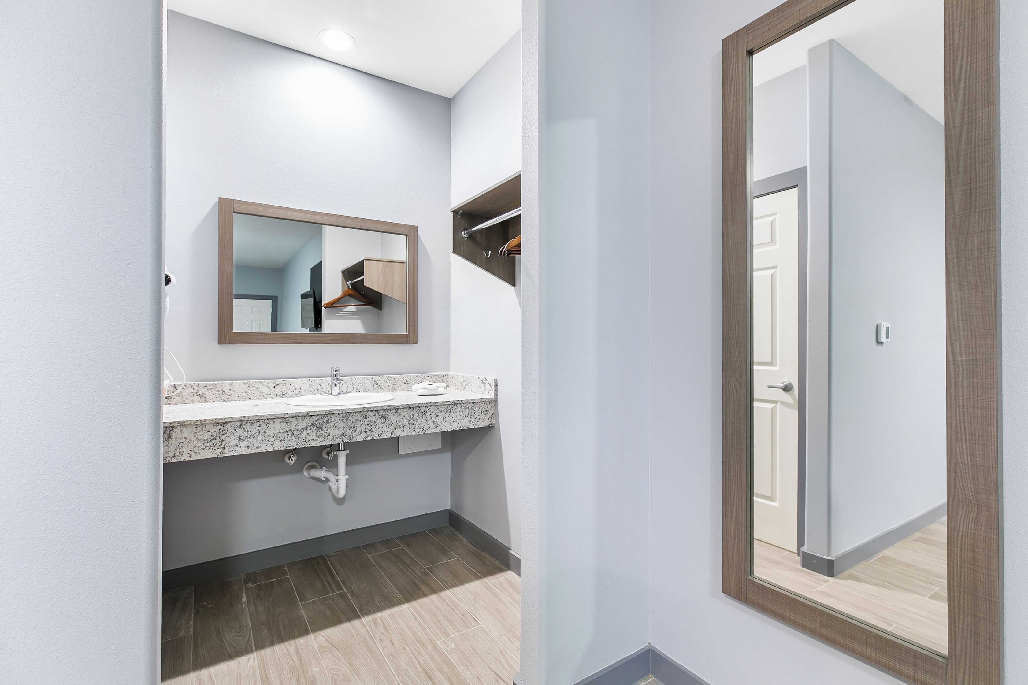 A modern bathroom with a granite countertop sink, a mirror, and a towel rack.