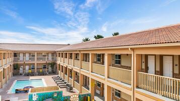 Guests can enjoy a refreshing swim in the central pool surrounded by lounge chairs and a vibrant mural.