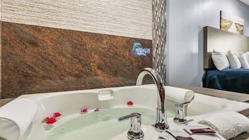 A modern bathroom with a large bathtub, a mirror, and a wooden wall.