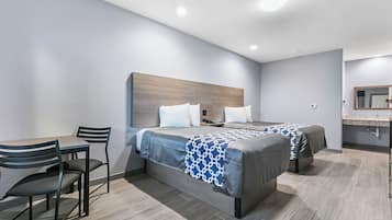 A modern hotel room with two beds, a desk, and a chair.