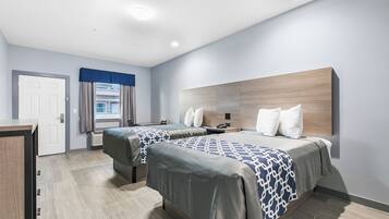 Une chambre d’hôtel moderne avec deux lits, un bureau et une grande fenêtre avec des rideaux.