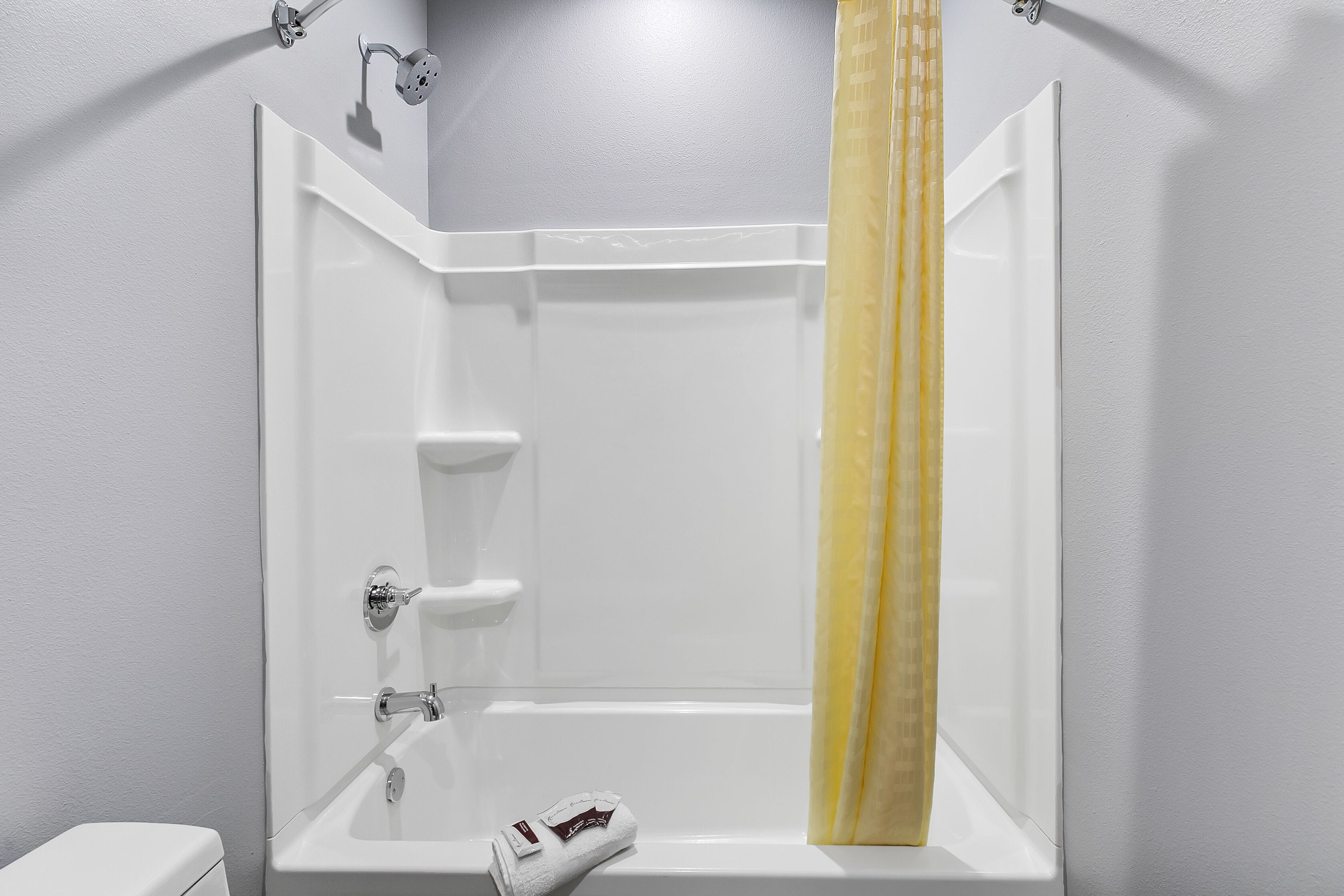 Une salle de bain moderne avec une baignoire blanche, une pomme de douche et un porte-serviettes.