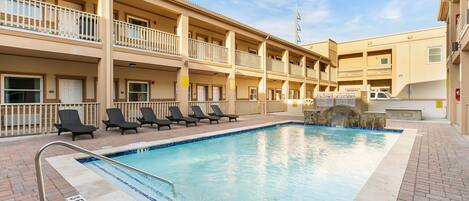 Un hotel con piscina, varios balcones y un camino de ladrillo.