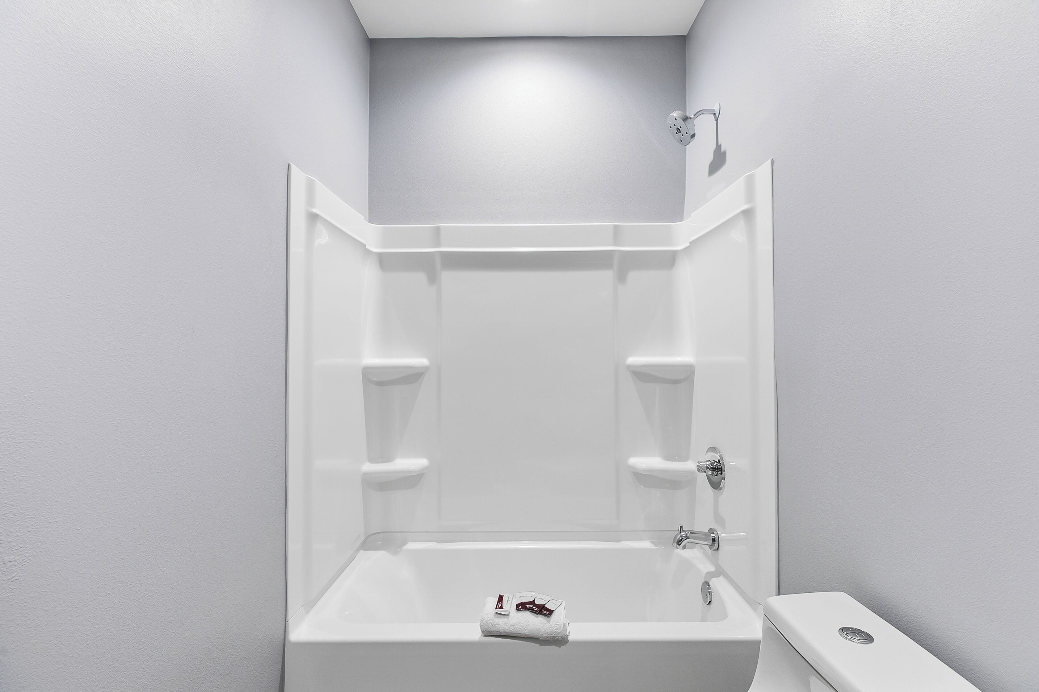 A modern bathroom with a bathtub, two towel racks, and a toilet.