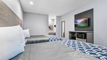 Ein modernes Hotelzimmer mit einem großen Bett, einem flachbildfernseher an der Wand und einer Mikrowelle in der Ecke.