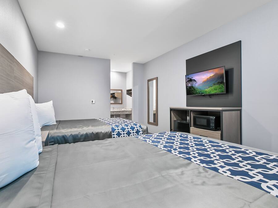 Ein modernes Hotelzimmer mit einem großen Bett, einem flachbildfernseher an der Wand und einer Mikrowelle in der Ecke.