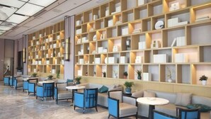 Un lobby moderno con una gran estantería, zonas de estar y un piso de mármol.