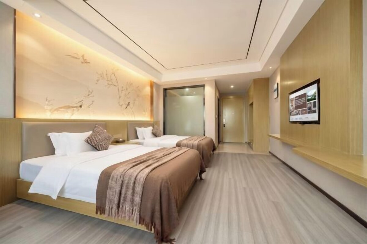 A hotel room with a large bed, a bedside table, a wall-mounted TV, and a wooden accent wall.