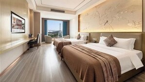 Habitación de hotel con dos camas, un escritorio, una silla, un ventanal grande y un cuadro colgado en la pared.