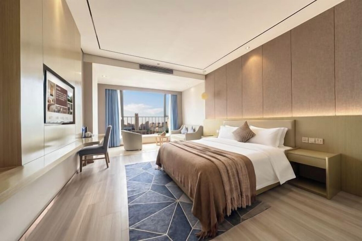 Et moderne hotelværelse med en stor seng, et siddeområde og udsigt til byen.