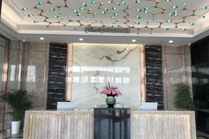 Een receptiegedeelte met een marmeren receptiebalie, een vaas met bloemen en een decoratief plafond.