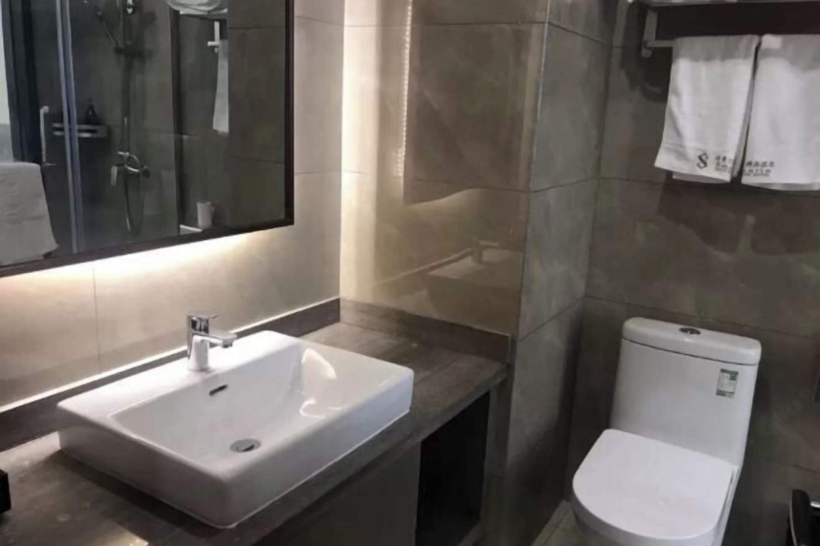 Uma casa de banho moderna com uma sanita, um lavatório e um espelho.