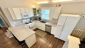A kitchen with white cabinets, a stove, a microwave, a dishwasher, and a refrigerator. - Mass Ave & Bottleworks + Garage parking (Indianapolis)
