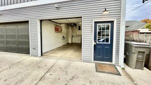 A garage with a closed door, a blue front door, and a visible garage door opener. - Mass Ave & Bottleworks + Garage parking (Indianapolis)
