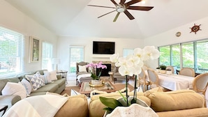 A spacious living room with a ceiling fan, a fireplace, and a dining area with a table and chairs. - Free Daily Golf Villa · Private Island · 4BR/4BA · 25 min to Hilton Head (Okatie)