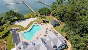 An aerial view of a resort with a swimming pool, lounge chairs, and a dock extending into a lake. - Free Daily Golf Villa · Private Island · 4BR/4BA · 25 min to Hilton Head (Okatie)