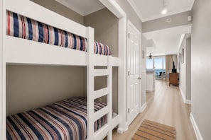 Une chambre avec des lits superposés, une porte, un couloir et une vue sur la mer.