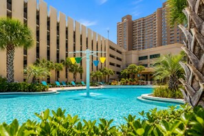 A hotel with a swimming pool surrounded by palm trees and lounge chairs. - Book Now! Fall on the Beach! Starbucks! Emerald Beach Resort. Beach Service! (Panama City Beach)