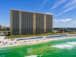 A high-rise hotel with a beach view, multiple balconies, and a beachfront with umbrellas and sun loungers. - Book Now! Fall on the Beach! Starbucks! Emerald Beach Resort. Beach Service! (Panama City Beach)