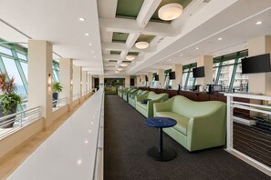 Eine moderne Hotelhalle mit einer langen Rezeption, einer grünen Lounge und großen Fenstern mit Aussicht.