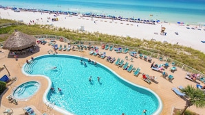 A large swimming pool with multiple lanes, surrounded by sun loungers and a beach view.